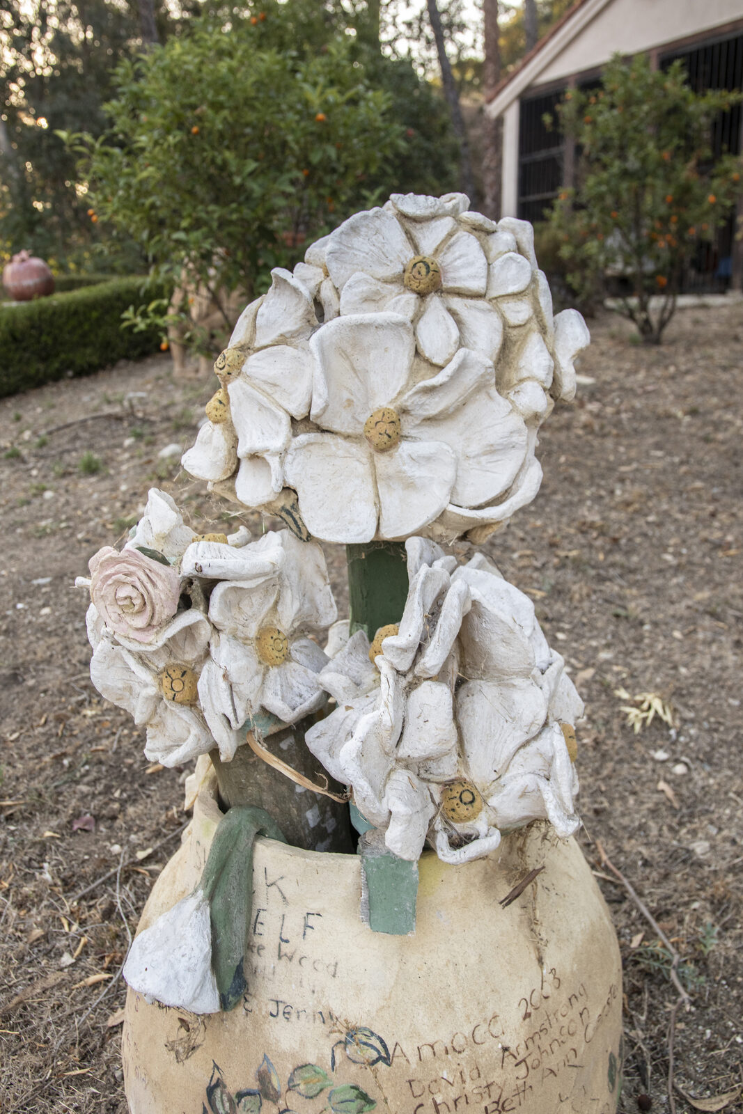 Ceramic vessel crowned with an armful of large white sculpted blossoms, with inscriptions on the body